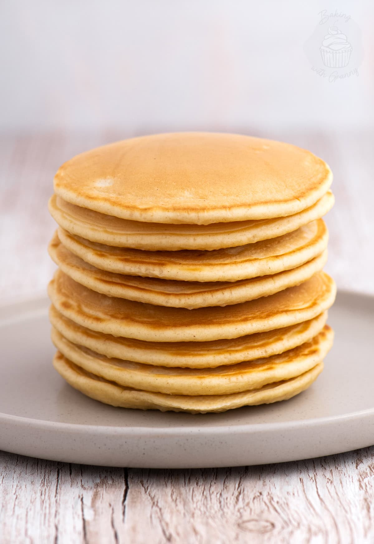 A stack of traditional golden Scotch Pancakes (Drop Scones) atop of a grey plate.