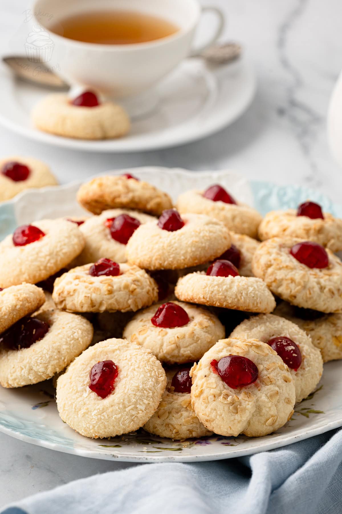 Melting Moments coated in oats and topped with glacé cherries, piled on a serving plate