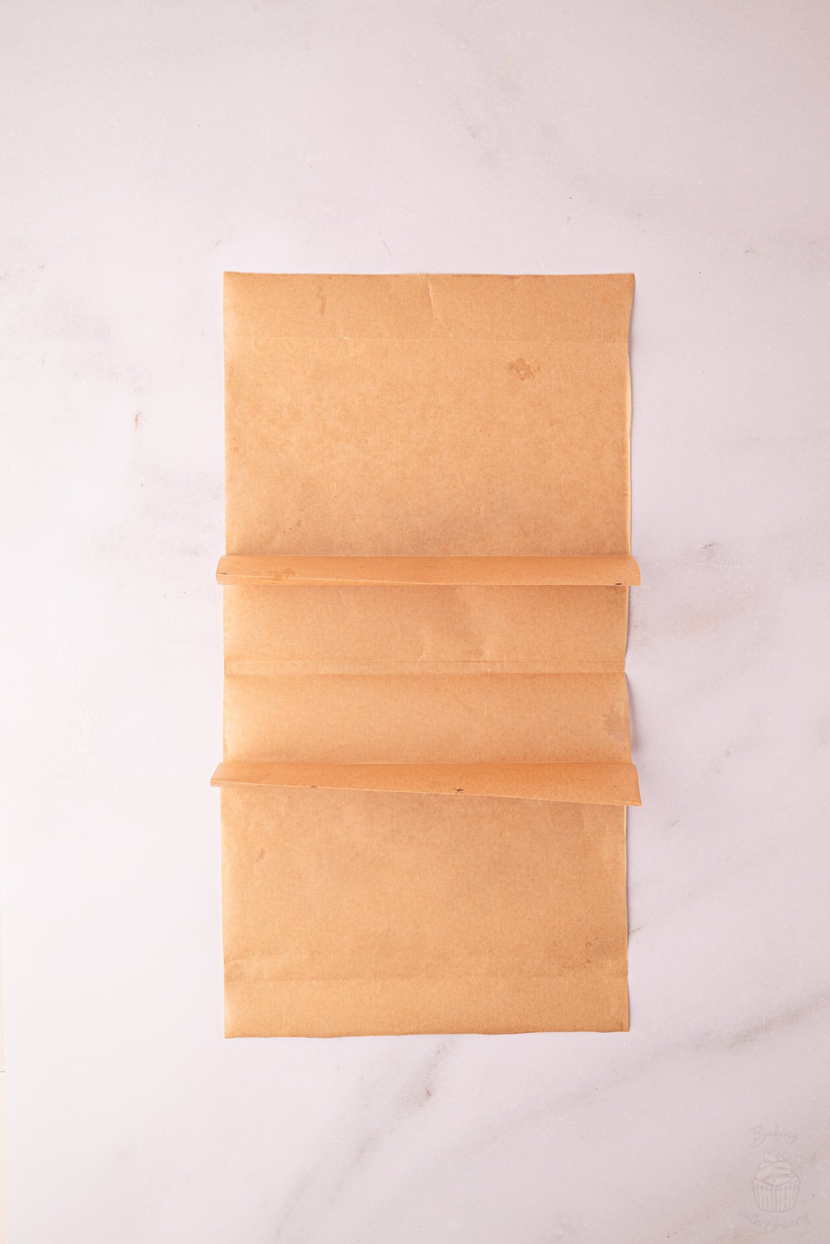 Two pleats folded into greaseproof paper to create three cake sections.