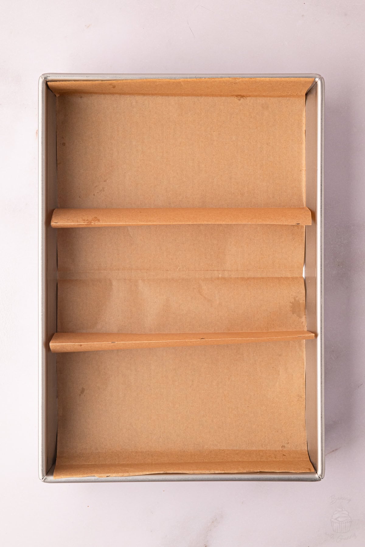 Folded greaseproof paper fitted inside a baking tin to create three sections.