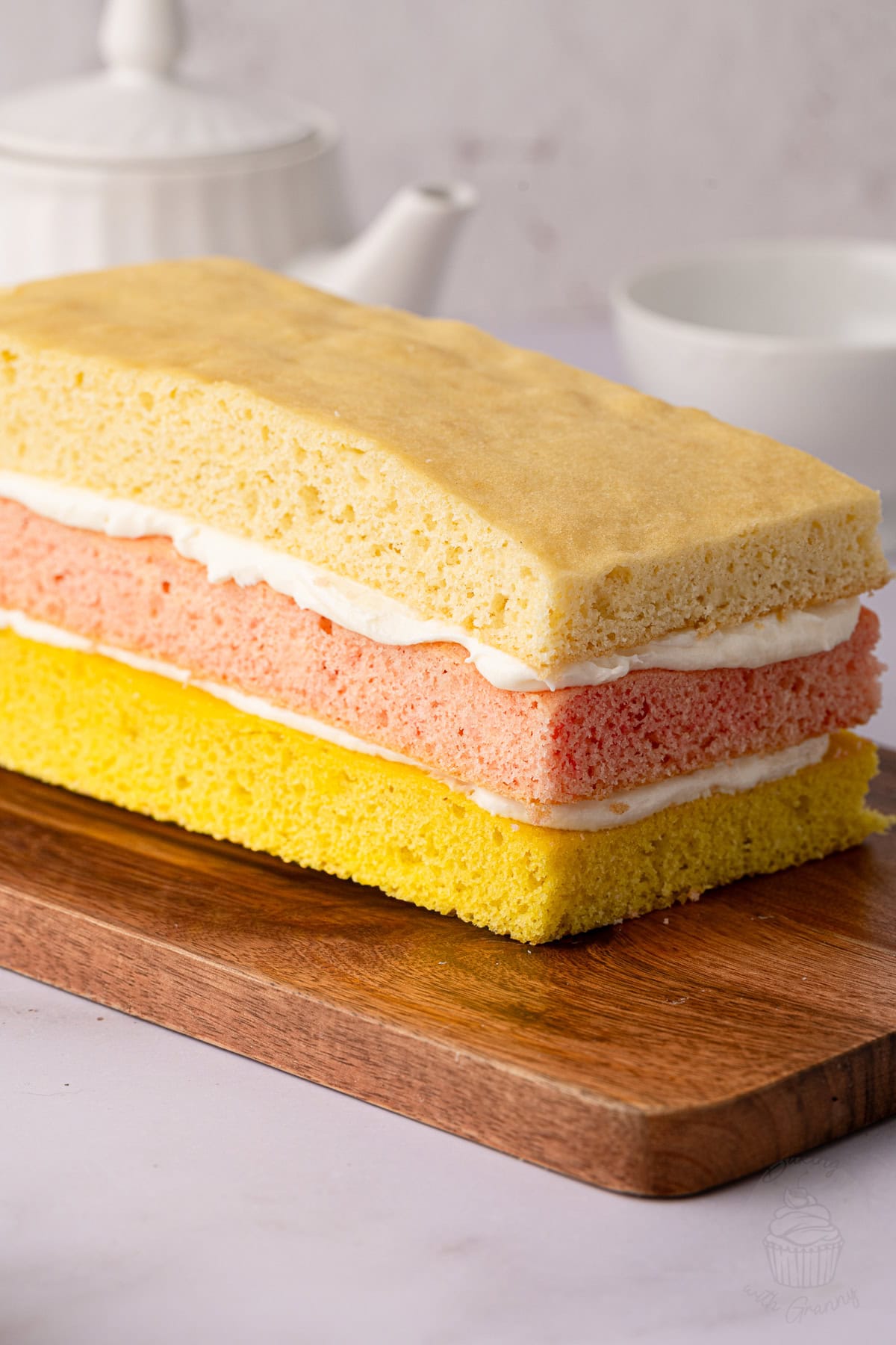 Homemade British Angel Cake with vanilla sponge layers coloured pink, yellow and plain, sandwiched with buttercream.