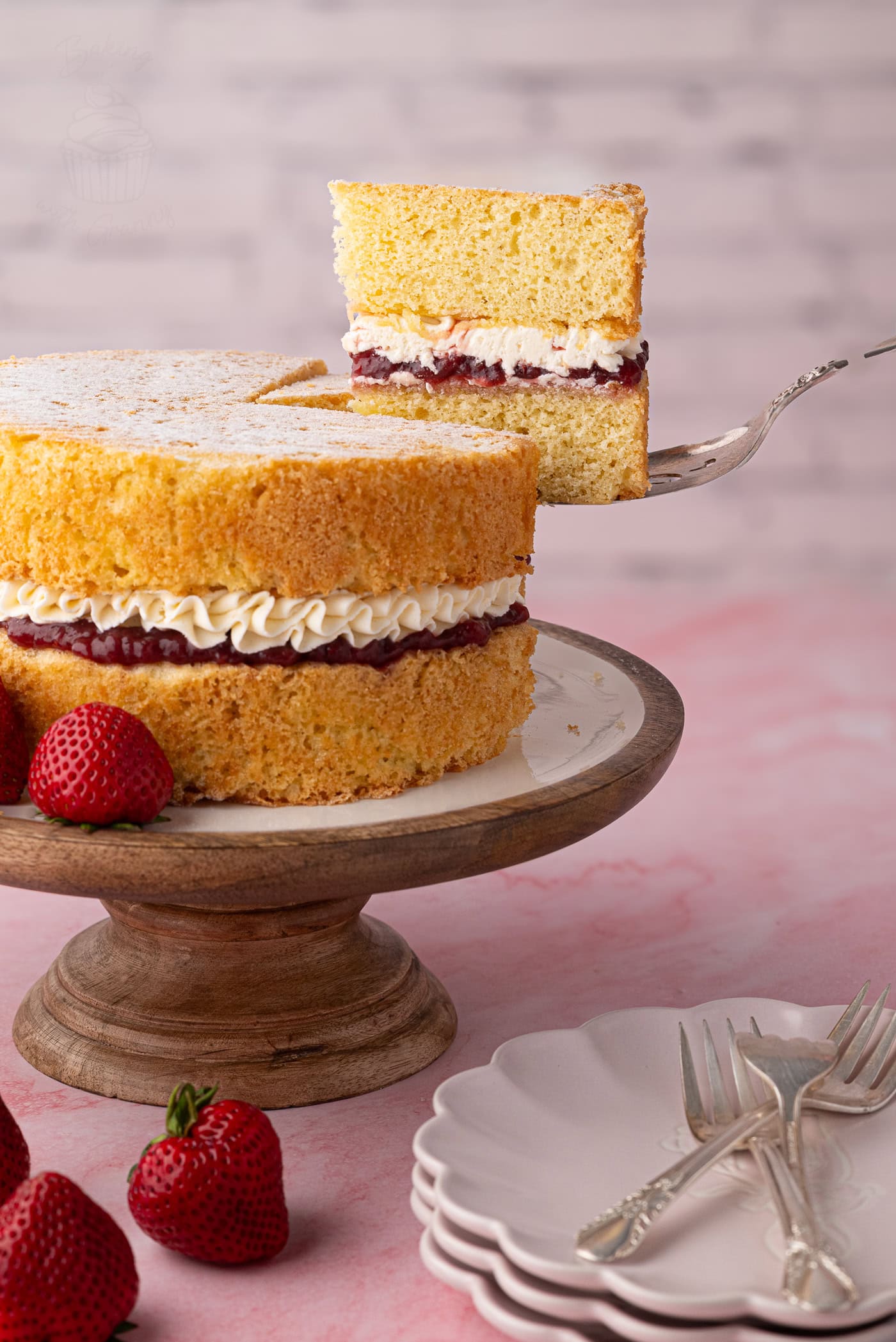 Slice of Victoria Sponge lifted from the cake, showing sponge, jam and buttercream layers.