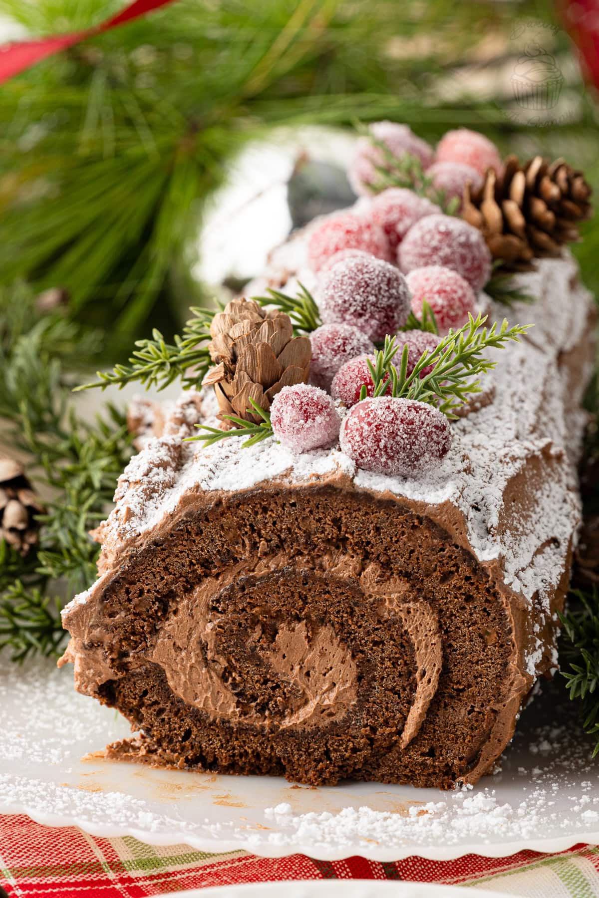 Decorated chocolate Yule Log with chocolate buttercream bark, icing sugar and festive decorations