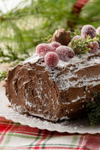 Finished chocolate Yule Log decorated with chocolate buttercream bark, icing sugar and festive decorations.
