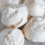 Pile of freshly baked meringues with cracked, glossy shells, part of an easy homemade meringue recipe.