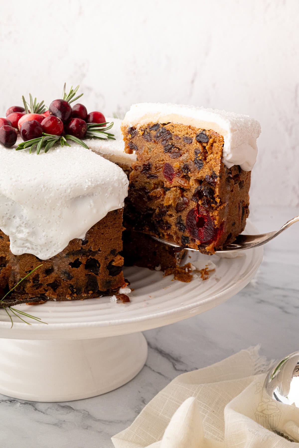 A slice of iced Christmas cake lifted from the cake on a silver server.