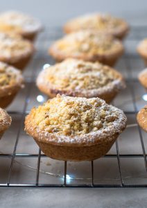 Crumble Top Mince Pies recipe from Baking with Granny. Delicious classic shortcrust mince pie, with a crumble topping, sat on top of a cooling rack, with Christmas lights twinkling underneath.