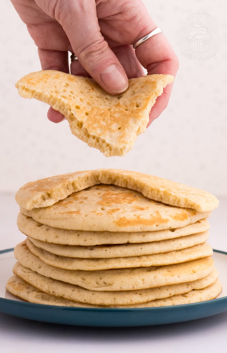 Hand lifting a piece of Scottish crumpet to show the soft, airy inside.