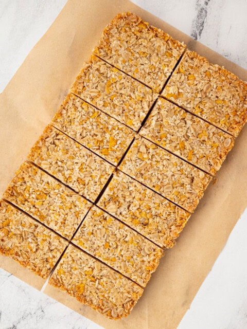 Overhead view of a full tray of honey slice cut into even bars on brown parchment paper.