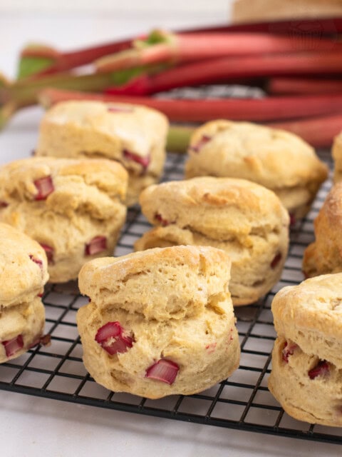Freshly baked Rhubarb Scones cooling on a wire rack, with freshly chopped rhubarb visible in the dough.