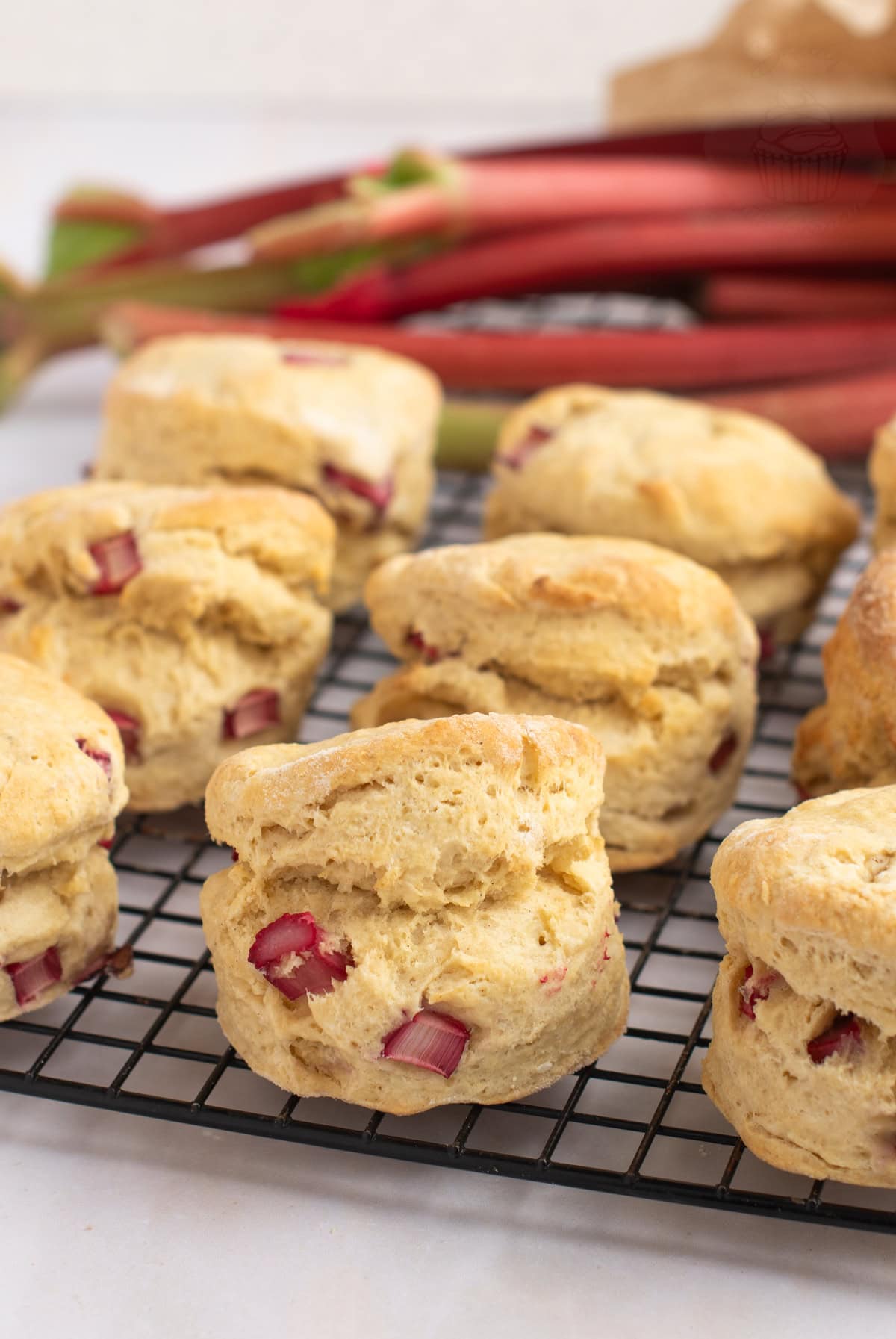 Freshly baked Rhubarb Scones cooling on a wire rack, with freshly chopped rhubarb visible in the dough.