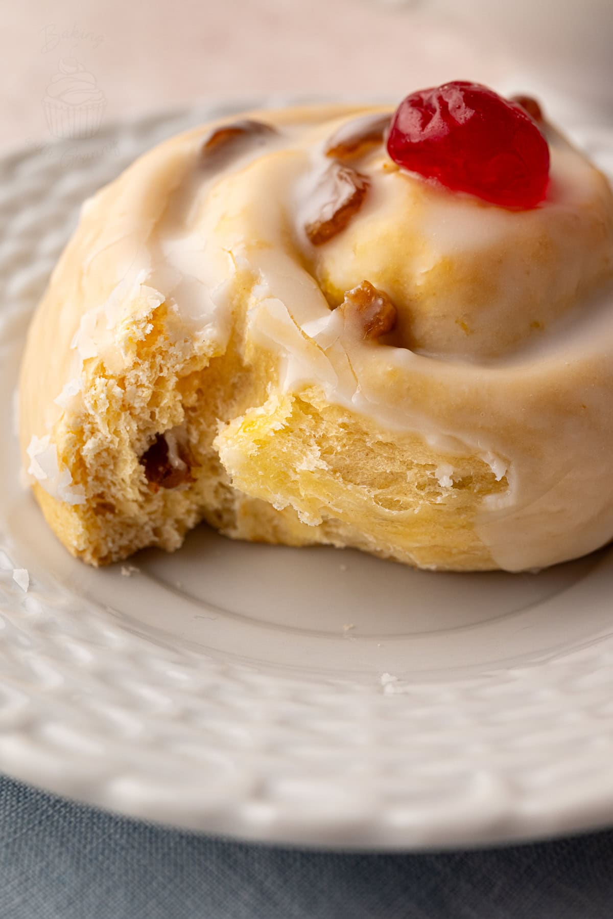 Close-up of the soft interior of a Belgian bun, showing icing, golden sponge, and juicy sultanas.
