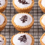 Overhead view of iced Fern Cakes with piped chocolate decorations, arranged neatly on a wire cooling rack.