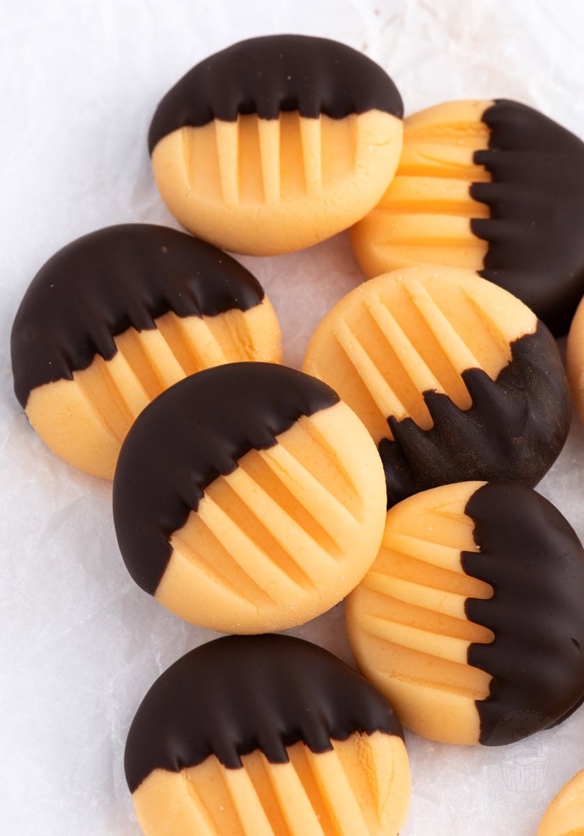 Homemade orange creams half-dipped in dark chocolate, arranged on baking paper - easy Christmas gift idea.