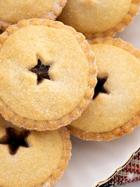 Overhead view of classic mince pies with star-shaped pastry tops, sprinkled with sugar, showing their traditional festive design.