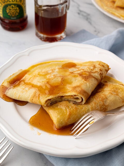 Traditional English-style pancakes folded and drizzled with golden syrup.