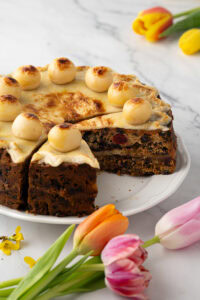 Close-up of Simnel Cake slice with visible dried fruit, glace cherries, and baked marzipan layer.