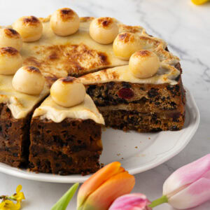 Close-up of Simnel Cake slice with visible dried fruit, glace cherries, and baked marzipan layer.