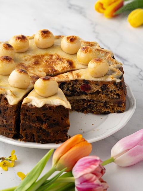 Close-up of Simnel Cake slice with visible dried fruit, glace cherries, and baked marzipan layer.