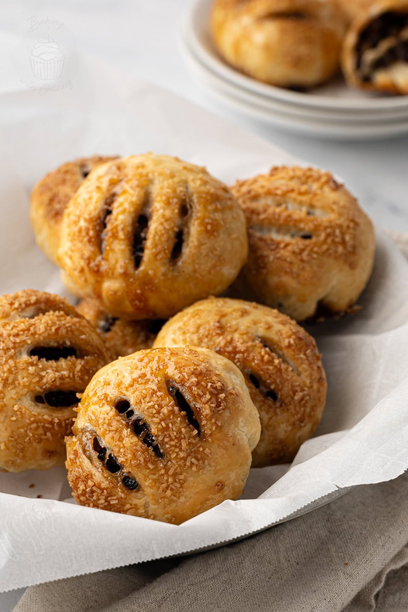 Golden brown Eccles cakes with sugar topping on baking paper.