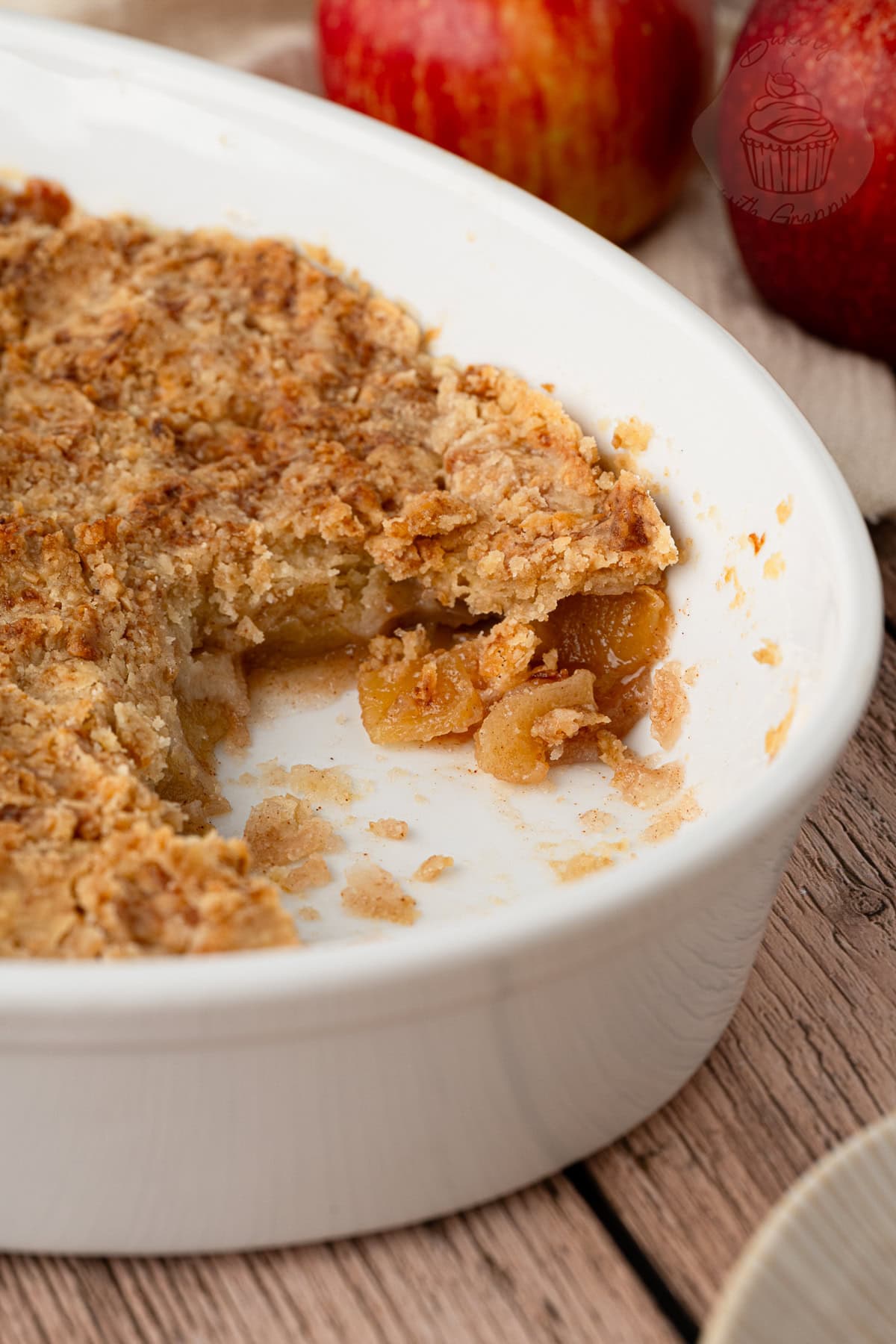 Apple crumble with a portion removed, showing the soft spiced apple filling