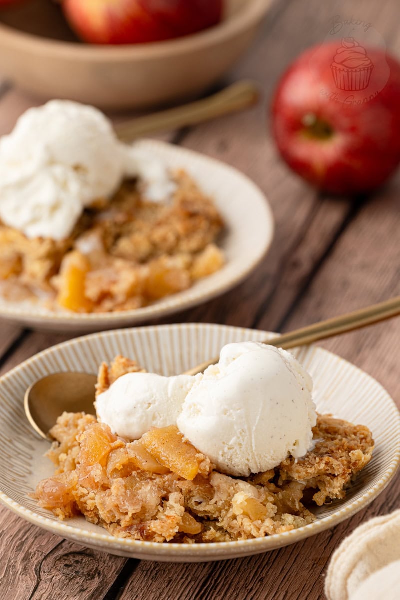 A plated serving of easy apple crumble with an oat-free topping, a scoop of vanilla ice cream, and fresh whole apples in the background.