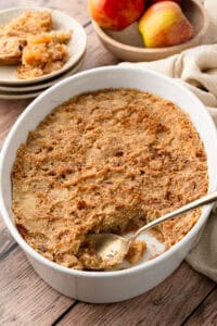 An easy apple crisp recipe baked to a perfect crisp crust, showing a gold spoon scooping out a serving.