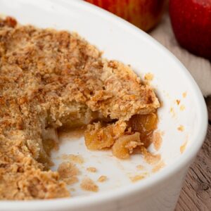 Close-up of baked apple crumble showing the soft apple filling beneath the topping.