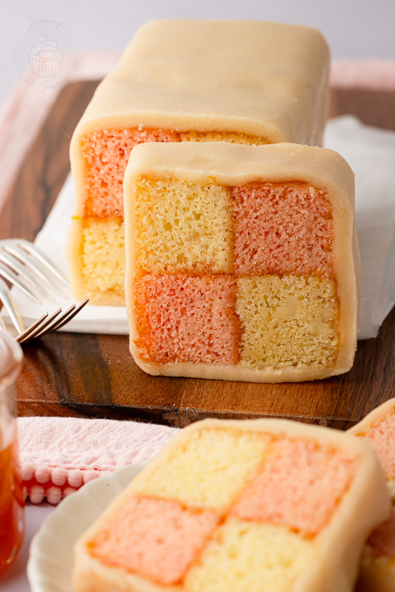 Battenberg cake showing four pink and plain sponge squares inside marzipan.