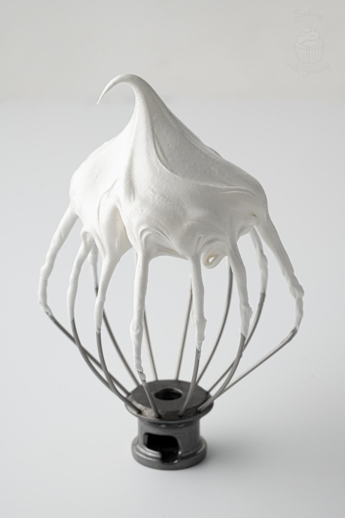 Glossy meringue for Pavlova holding a stiff peak on a whisk.