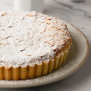 Bakewell Tart topped with flaked almonds and dusted with icing sugar.