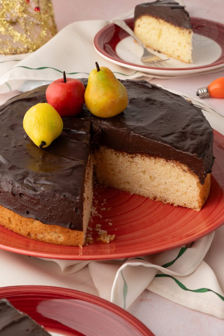Tunis Cake with a wedge removed, showing Madeira sponge beneath a thick chocolate topping.