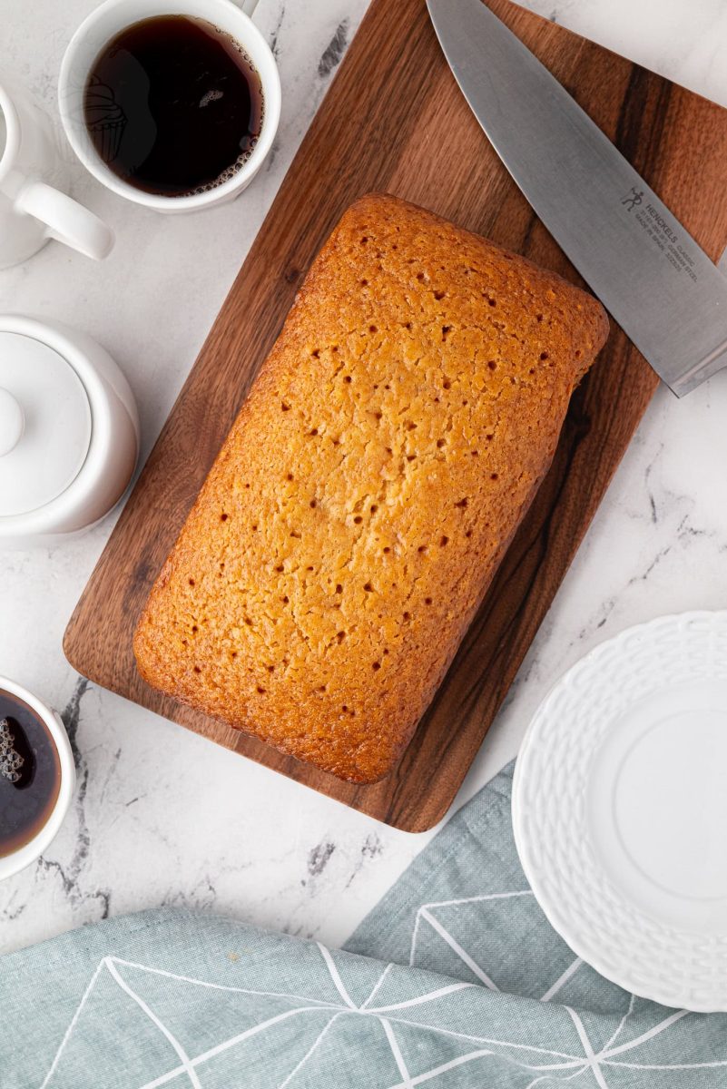 Golden Syrup Cake Overhead view of whole golden syrup cake with coffee and plates around it.