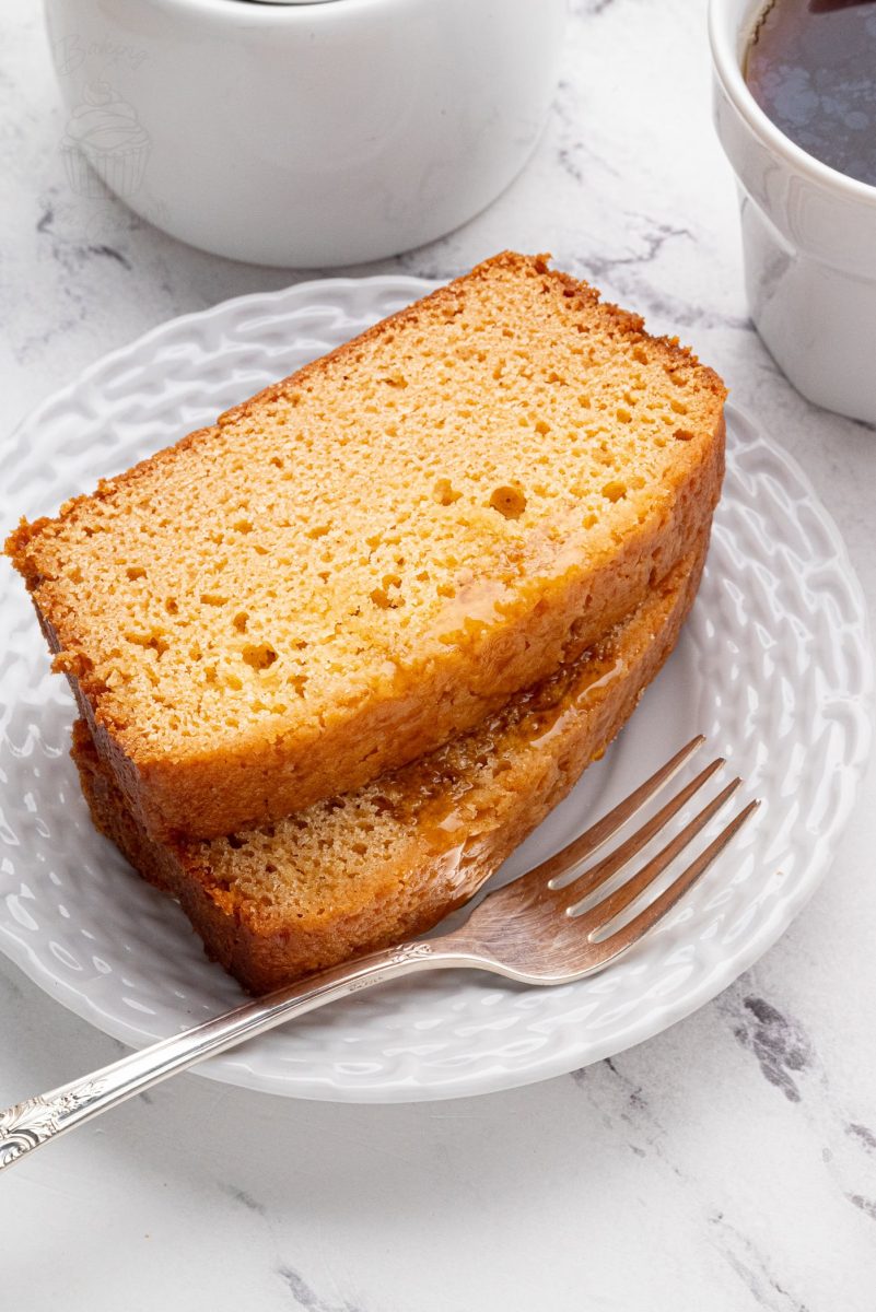 Golden Syrup Cake Two slices of golden syrup cake on a white plate with coffee cups.