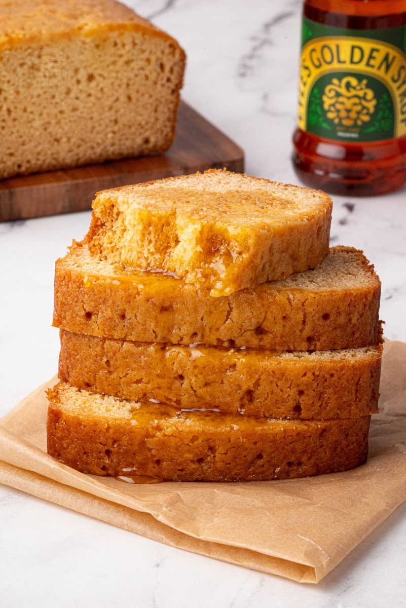 Golden Syrup Cake Close-up of golden syrup cake stack with syrup bottle and loaf in the background.