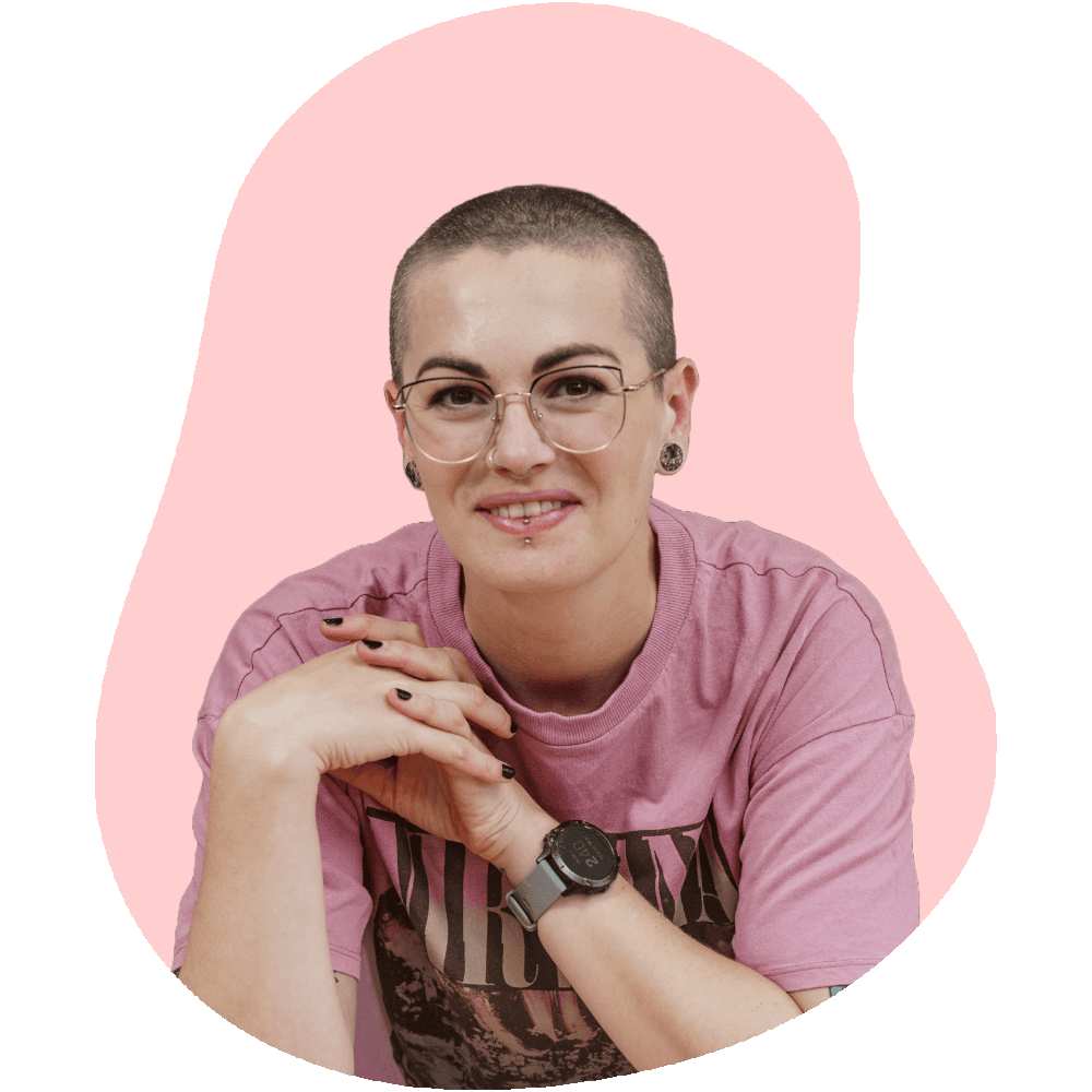 Headshot photo of Amy Reid, the creator of Baking with Granny. Amy has a shaved head, wears glasses and has a pink Nirvana t-shirt on.