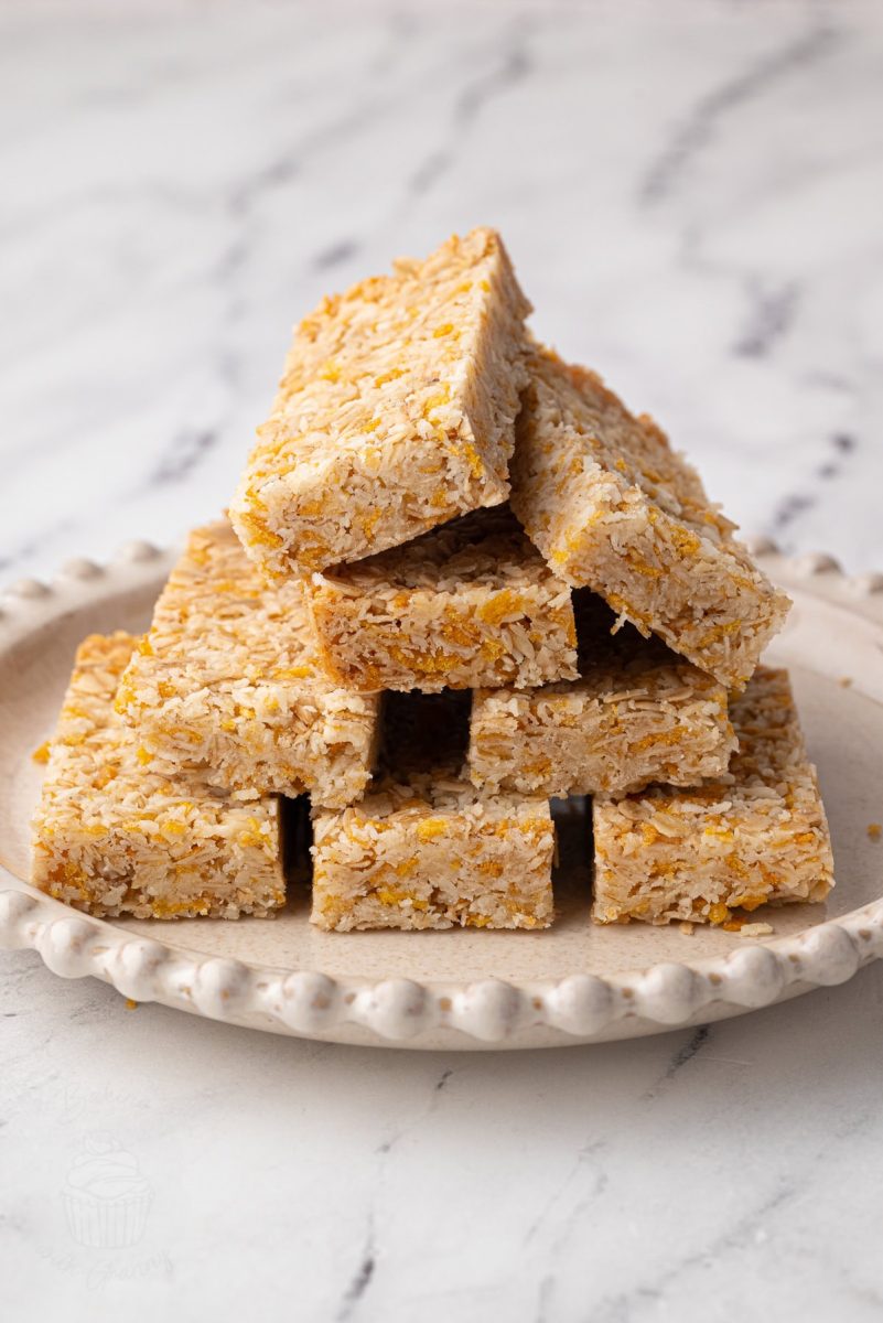 Honey Slice Honey slice bars arranged in a neat stack on a plate with visible layers of oats and coconut.