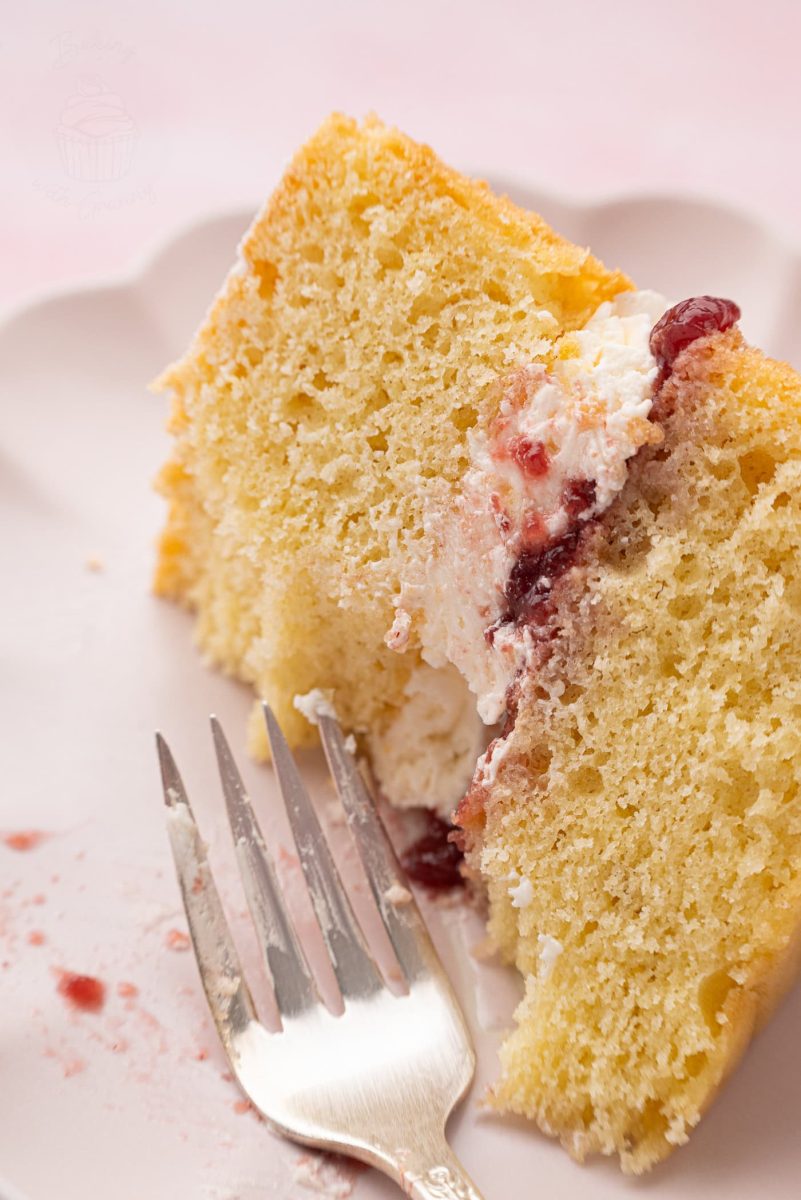 Victoria Sponge Close-up of a single bite of Victoria Sponge cake on a fork, showing the airy sponge and rich jam and cream centre.